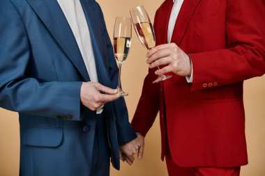 Two men in suits, one blue and one red, raise their champagne flutes in a celebratory toast. clipart