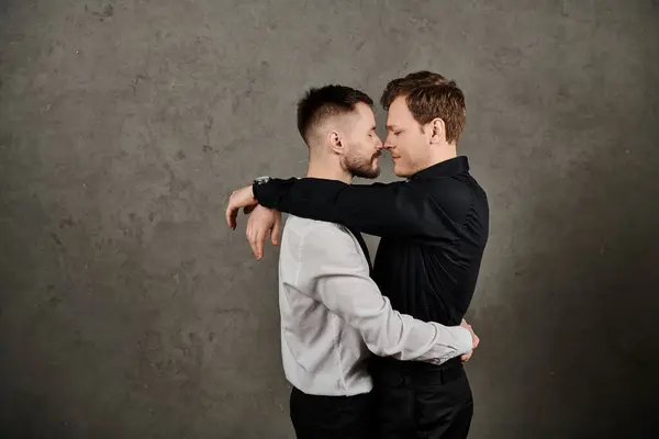 stock image Two men in suits embrace passionately against a textured concrete wall.