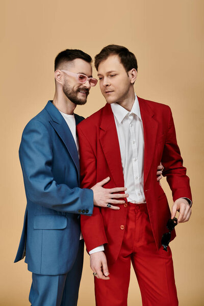 Двое мужчин в элегантных костюмах стоят близко друг к другу, с одной рукой вокруг другой талии.