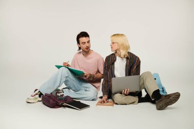 İki genç eşcinsel öğrenci yerde oturuyor ve birlikte ders çalışıyorlar..