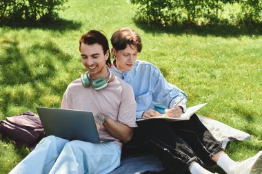 Two friends in casual attire spend time outdoors, one using a laptop and the other writing in a notebook. clipart