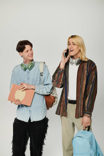 Two young students, one wearing a blue shirt and the other a striped shirt, stand in a studio and smile.
