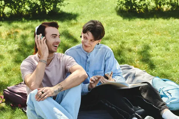 stock image Two young friends, wearing casual attire, laugh and relax on a grassy outdoor area.