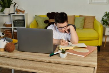 Down sendromlu bir çocuk masada oturmuş ders çalışıyor..