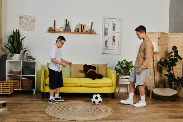 Two young boys play soccer indoors.