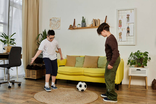 Two young boys play soccer indoors.