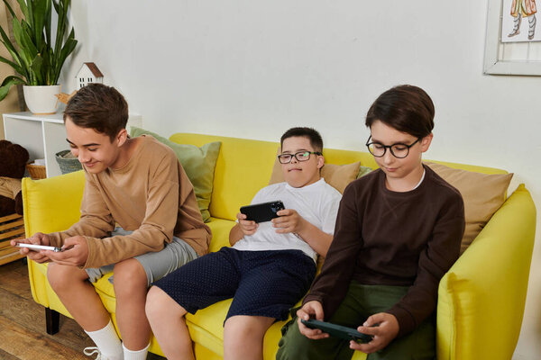Три мальчика сидят на жёлтом диване и играют в игры на телефонах..