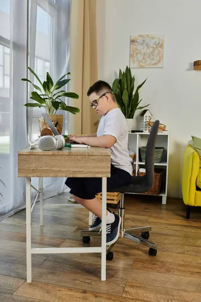 stock image A young boy with Down syndrome sits at his desk, focused on his work.