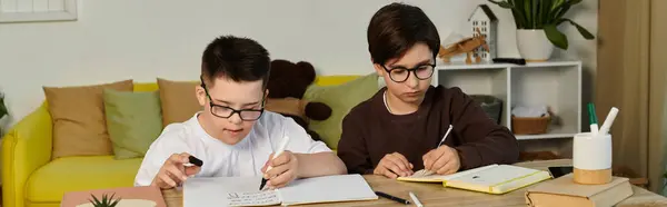 stock image Two young boys, one with Down syndrome, concentrate on their homework at home.