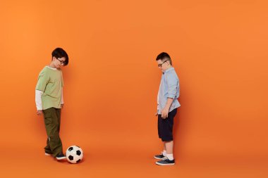 İki çocuk stüdyo ortamında futbol oynuyor..
