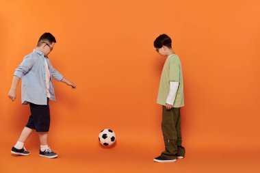 İki çocuk, biri Down sendromlu, futbol oynuyor..