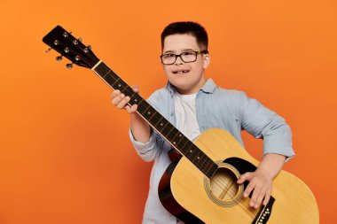 Genç bir çocuk akustik gitar çalarken gülümsüyor..