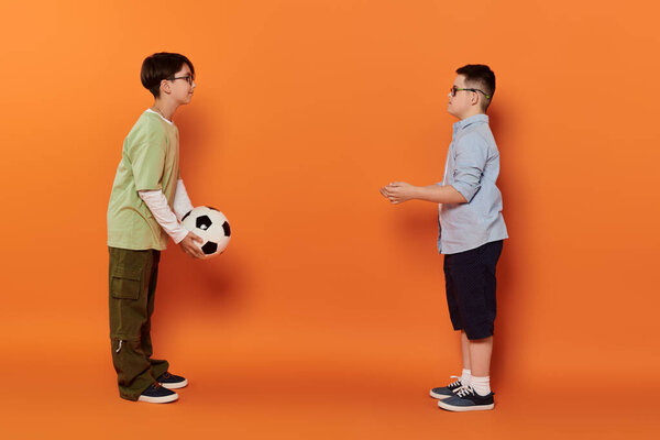 Two young boys play soccer indoors.