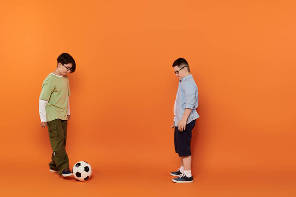 Two boys play soccer in a studio setting.