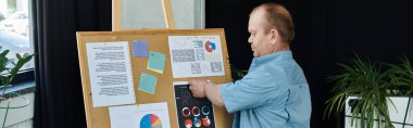 Kapsamlı bir adam bir mantar panonun yanında grafik ve grafikleri sunuyor..