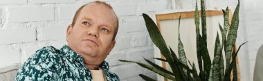 Şablon gömlekli bir adam düşüncelere dalmış, yemyeşil bir çiçek gibi..