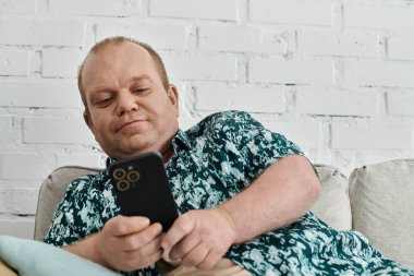 Kapsamlı bir adam kanepede oturmuş telefonuna bakıyor..