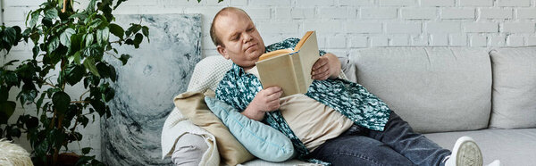 Человек с инклюзивностью лежит на диване с книгой, наслаждаясь моментом покоя и отдыха.