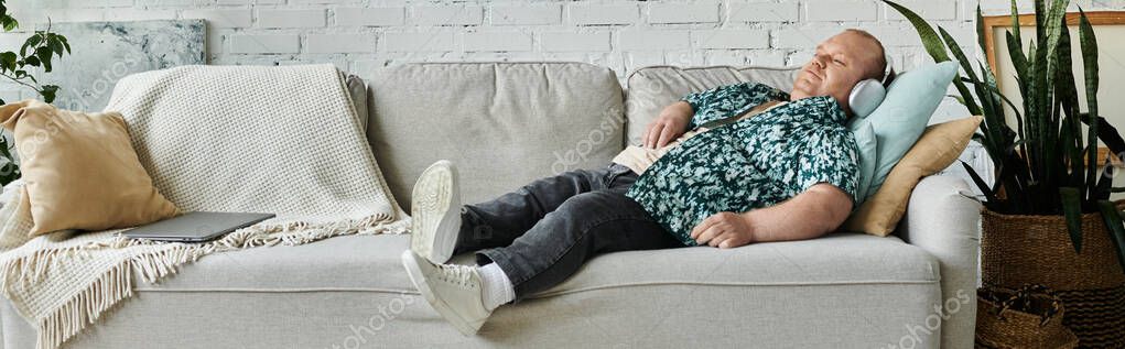 Человек с инклюзивностью лежит на диване, слушая музыку через наушники.