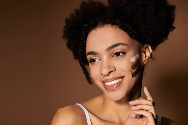 A young woman with a bright smile shows off different skin tone swatches on her cheek.