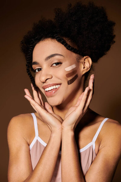 A young African American woman with a warm smile poses for a portrait. She has a variety of makeup colors on her cheek.