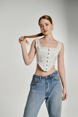 Sarı saçlı, beyaz korse ve mavi kot giyen genç bir kadın..