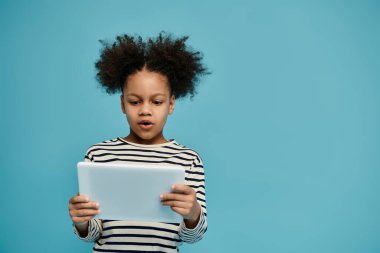 Kıvırcık saçlı genç bir Afrikalı Amerikalı kız çocukluğunda teknolojinin gücünü gösteren tabletine dikkatle bakıyor..