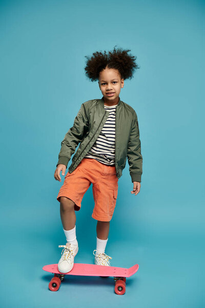 A young African American girl with curly hair poses on a pink skateboard against a blue background.