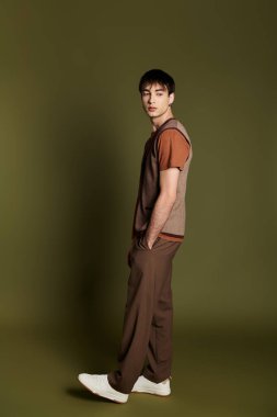 Şık bir adam canlı yeşil bir zemine karşı özgüvenle poz verir..