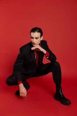 Takım elbiseli ve kravatlı şık bir adam, canlı arka planda poz veriyor..