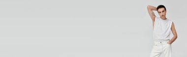 Beyaz askılı şık bir adam beyaz bir arkaplanda poz veriyor..