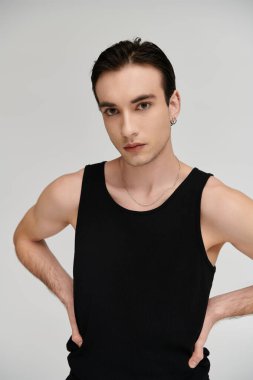 A man poses confidently in a black tank top against a white background. clipart