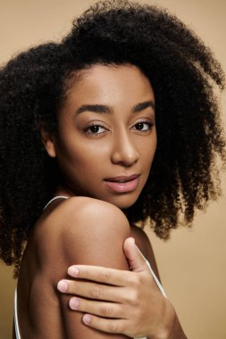 Bej arka planda doğal makyajlı güzel bir Afro-Amerikan kadının yakın plan portresi..