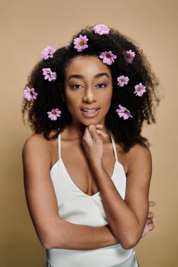 Güzel bir Afro-Amerikalı kadın, doğal makyajlı ve saçlarında çiçekler, usulca gülümsüyor..