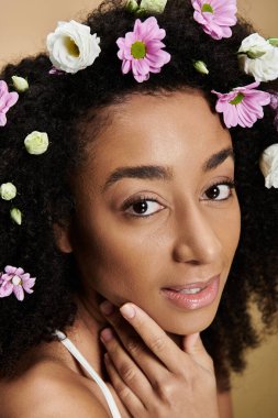 Güzel bir Afro-Amerikalı kadın, doğal makyajı ve bej arka planda çiçekleri var..