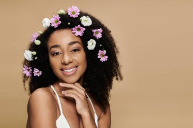 Güzel bir Afro-Amerikan kadının portresi. Doğal makyajı ve saçlarında bej bir arka planda çiçekler..