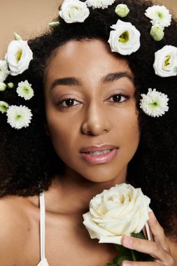 Saçında beyaz çiçekler ve doğal makyajlı güzel bir Afro-Amerikalı kadın yakın plan portresi için poz veriyor..