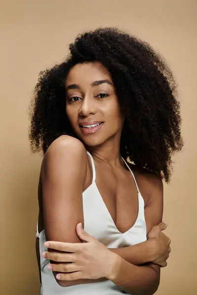 stock image A beautiful African American woman with natural makeup smiles confidently against a beige background.