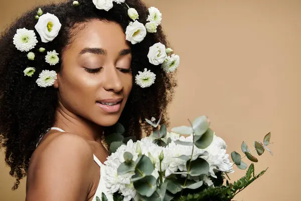 stock image A beautiful African American woman with natural makeup and white flowers in her hair, against a beige backdrop.