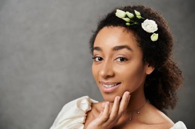 Beyaz elbiseli, güzel bir Afro-Amerikan gelini. Saçında çiçekler, hafifçe gülümsüyor..