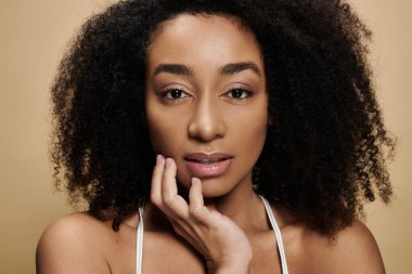 Bej arka planda doğal makyajlı güzel bir Afro-Amerikan kadının yakın plan portresi..