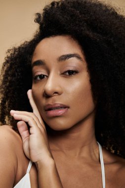 Güzel bir Afro-Amerikan kadının yakın plan portresi doğal makyajlı, bej bir arka planda parlayan teni.