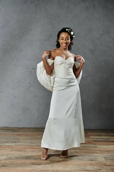 stock image Beautiful bride with flowers in hair posing in white wedding dress on grey background.