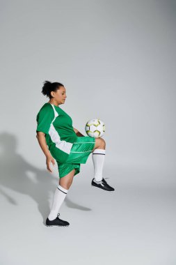 Yeşil formalı ve şortlu bir bayan atlet bir futbol topunu ustalıkla hokkabazlık yaparak çeviriyor..