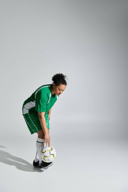 Yeşil futbol formalı atletik bir kadın eğiliyor, pas vermeye hazır..