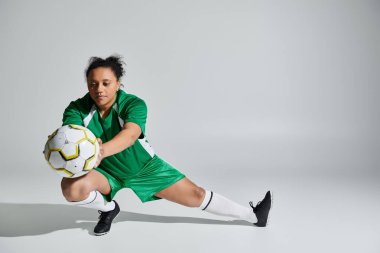 Yeşil futbol formalı bir bayan sporcu, beyaz bir arka planda, oynamaya hazır..