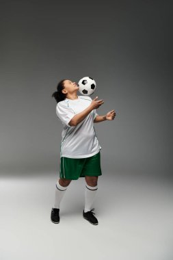 Dişi bir sporcu, kafası stüdyoda bir futbol topuyla hokkabazlık yapıyor..