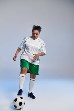 A woman in a white jersey and green shorts dribbles a soccer ball. clipart