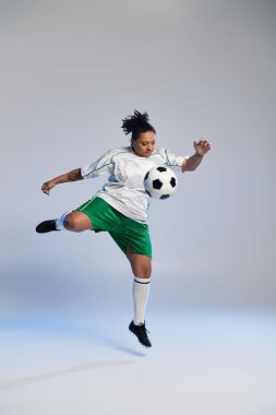 Female athlete kicks soccer ball in mid-air during photoshoot. clipart