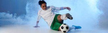 Beyaz formalı ve yeşil şortlu bir bayan sporcu futbol oynuyor..
